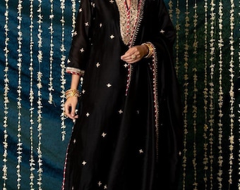 May include: A black embroidered kurta with gold and red trim. The kurta is paired with matching trousers and a dupatta. The fabric is sheer and has a subtle sheen.