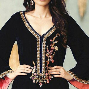 May include: Black velvet dress with long sleeves and a V-neckline. The dress features intricate gold and white embroidery along the neckline and sleeves, with floral embroidery on the bodice. The sleeves have a contrasting pink lining.