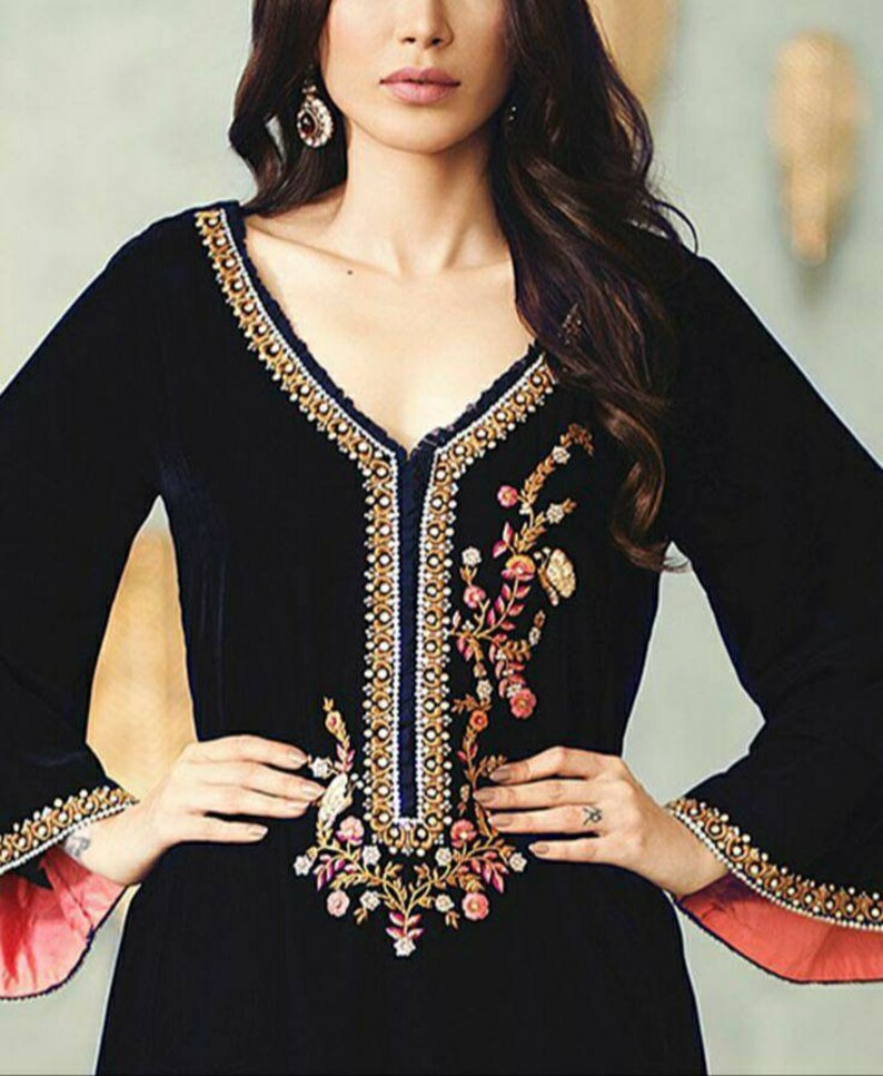 May include: Black velvet dress with long sleeves and a V-neckline. The dress features intricate gold and white embroidery along the neckline and sleeves, with floral embroidery on the bodice. The sleeves have a contrasting pink lining.