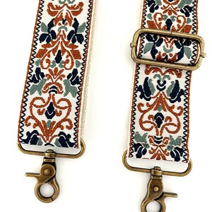 May include: A replacement bag strap featuring a woven pattern in rust orange, sage green, and navy blue on a cream background. The strap includes antique brass-toned metal swivel lobster clasps and an adjustable sliding buckle for length control.