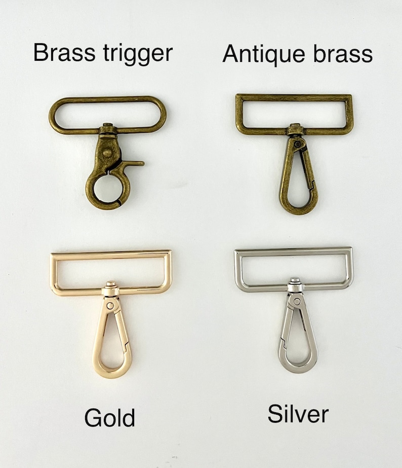 May include: Four metal swivel snap hooks with rectangular loops. Top left is labelled Brass trigger, top right is Antique brass, bottom left is Gold, and bottom right is Silver. Each hook features a spring-loaded gate and a rotating swivel base.