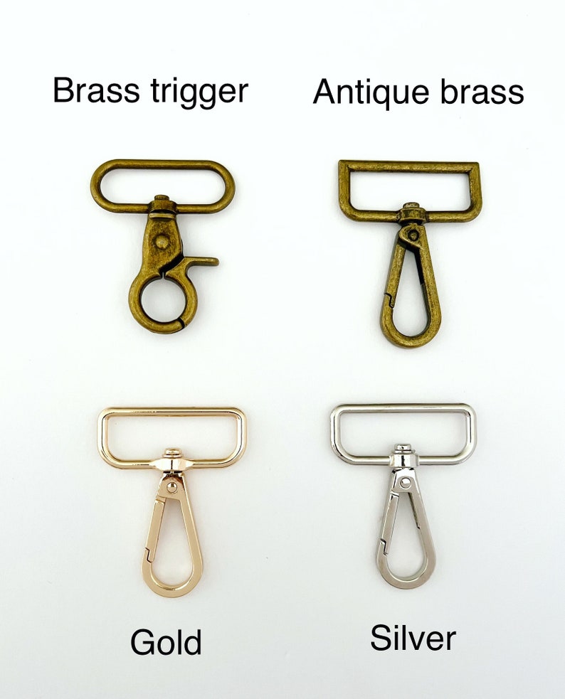 Op de afbeelding: Vier verschillende soorten triggergespen, waaronder messing trigger, antiek messing, goud en zilver. Elke gesp heeft een rechthoekige bovenste balk en een haak.