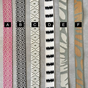 Op de afbeelding: Zes verschillende soorten geweven lint, gelabeld van A tot en met F. De linten zijn allemaal ongeveer 2,5 cm breed en hebben verschillende patronen en kleuren, waaronder roze, zwart, wit, grijs en bruin.