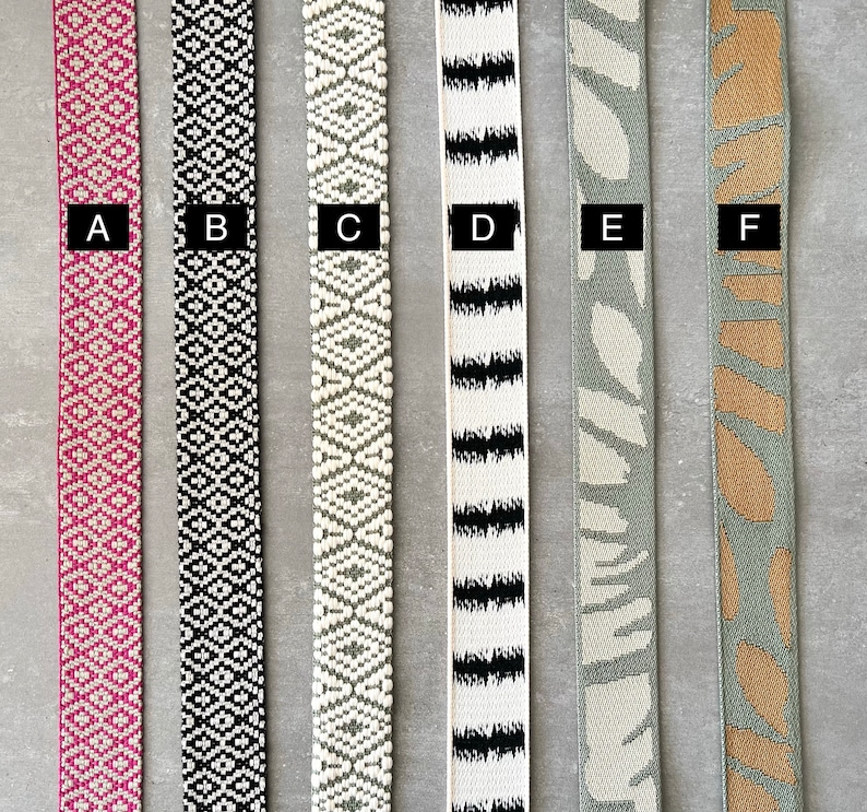 Op de afbeelding: Zes verschillende soorten geweven lint, gelabeld van A tot en met F. De linten zijn allemaal ongeveer 2,5 cm breed en hebben verschillende patronen en kleuren, waaronder roze, zwart, wit, grijs en bruin.