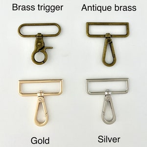 May include: Four different types of metal trigger clasps. The clasps are in brass trigger, antique brass, gold, and silver finishes. Each clasp has a rectangular loop and a trigger hook.