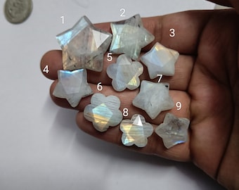 May include: Nine iridescent rainbow moonstone cabochons in various star and flower shapes. The stones are white with a rainbow sheen.