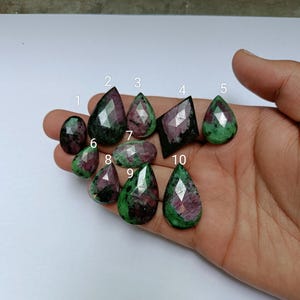 May include: Ten green and pink gemstone cabochons in various shapes, including teardrop and square, numbered 1 through 10.