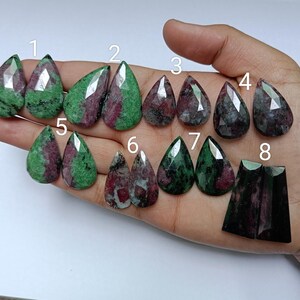 May include: Assortment of 8 green and pink gemstone drops, numbered 1 through 8. The stones are faceted and have a pear shape.
