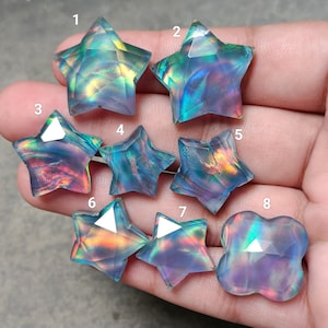 以下が含まれることがあります： 虹色の光沢を持つ、青、紫、ピンクの色の星形のカボションが8つと、花の形をしたカボションが1つあります。
