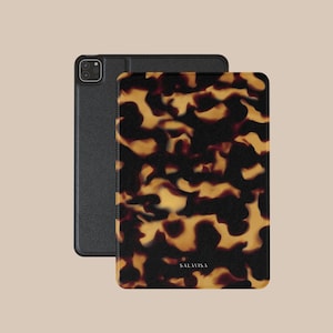 Op de afbeelding: Twee tablethoezen. Eén is zwart, de andere heeft een schildpadpatroon in tinten bruin, zwart en geel. Op de schildpadhoes staat het woord "SALAVISA" gedrukt. De hoezen zijn rechthoekig met afgeronde hoeken.