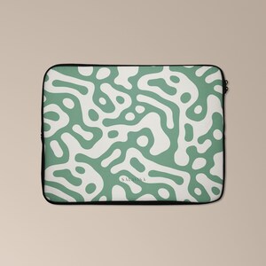 Könnte beinhalten: Eine grüne und weiße Laptoptasche mit einem abstrakten Muster. Die Tasche hat einen schwarzen Reißverschluss und der Text "SALV183" ist unten aufgedruckt.