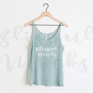May include: A light blue tank top with the text "blissful mocks" printed in white on the front. The tank top is hanging on a wooden hanger against a white background.