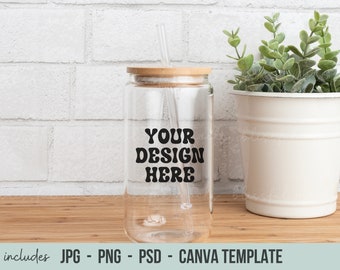May include: A clear glass water bottle with a bamboo lid and a straw. The bottle has a black sticker that says "YOUR DESIGN HERE".