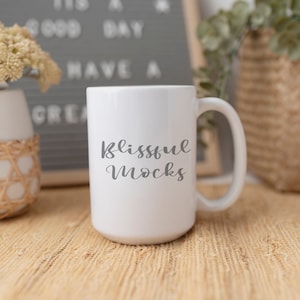 May include: White ceramic mug with a black handle. The mug has the text "blissful mocks" written on it in a cursive font.