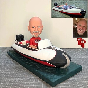 Könnte beinhalten: Eine personalisierte Bobblehead-Figur einer Person, die ein rotes Trikot der Kansas City Chiefs trägt, sitzt in einem weißen und schwarzen Schnellboot mit einem roten Streifen. Das Boot befindet sich auf einem grünen Sockel, der Wasser nachahmt.
