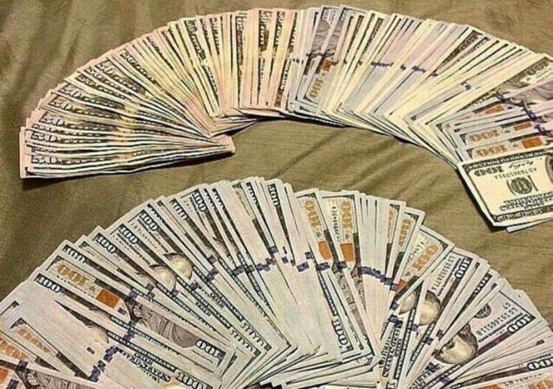 Pu&ograve; includere: Due grandi ventagli di banconote da cento dollari statunitensi, a ventaglio su una superficie strutturata. Le banconote sono nuove e nitide, con il ritratto di Benjamin Franklin visibile su ciascuna.