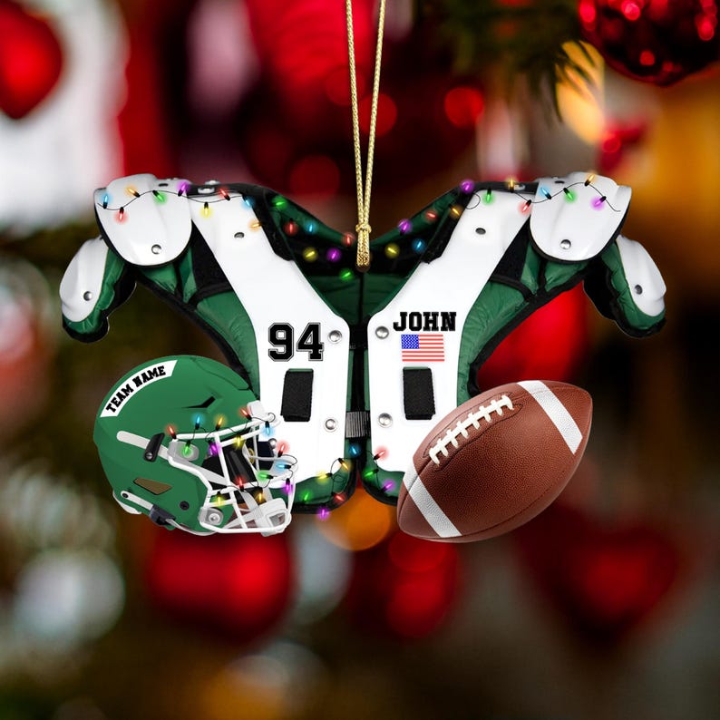 K&ouml;nnte beinhalten: Ein weihnachtlicher Football-Ornament mit gr&uuml;n-wei&szlig;en Schulterpolstern, einem gr&uuml;nen Helm mit der Aufschrift "TEAM NAME" und einem braunen Football. Das Ornament ist mit kleinen, bunten Lichtern geschm&uuml;ckt und tr&auml;gt den Namen "JOHN" und die Nummer "94".