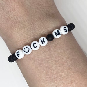May include: Black and white beaded bracelet with the word "F*CK MS" spelled out.