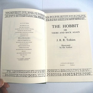 K&ouml;nnte beinhalten: Der Hobbit, oder Hin und Zur&uuml;ck von J.R.R. Tolkien. Ein Vintage-Buchcover mit wei&szlig;em Hintergrund und schwarzem Text. Das Buch ist vom Autor illustriert.