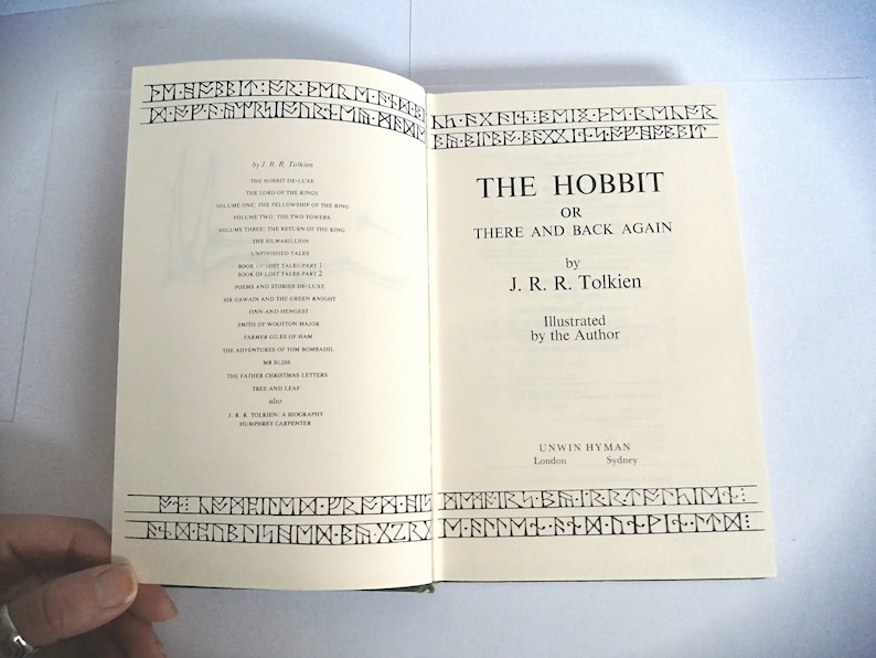 K&ouml;nnte beinhalten: Der Hobbit, oder Hin und Zur&uuml;ck von J.R.R. Tolkien. Ein Vintage-Buchcover mit wei&szlig;em Hintergrund und schwarzem Text. Das Buch ist vom Autor illustriert.