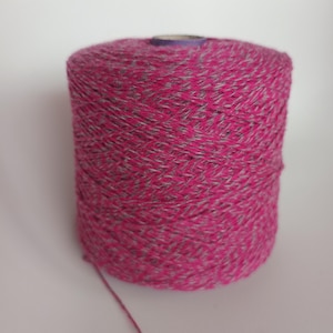 Peut inclure: Une bobine de fil rose et blanc avec une surface texturée.