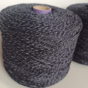 Peut inclure: Deux bobines de fil bleu foncé avec des reflets blancs. Le fil est enroulé autour d'une bobine en carton avec une étiquette en papier violet.