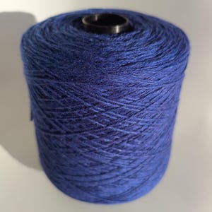 Peut inclure: Une pelote de laine bleue, enroulée serrée et prête à être tricotée ou crochetée.