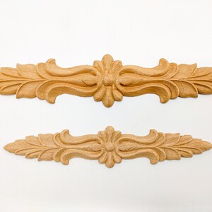 May include: Two wooden decorative trim pieces with a carved floral design. The larger piece is approximately 10 inches long and the smaller piece is approximately 6 inches long.