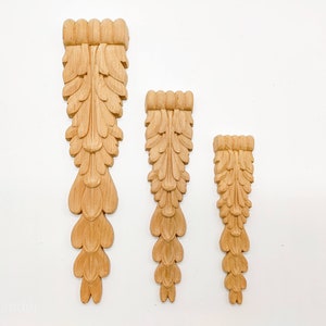 May include: Three wooden decorative pieces with a carved leaf design. The pieces are different sizes and are arranged in a row from largest to smallest.