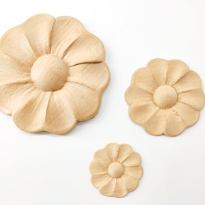 May include: Three wooden flower appliques in various sizes. The appliques are carved with a detailed floral design and have a natural wood finish.