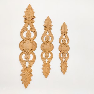 May include: Three wooden decorative wall ornaments with intricate carvings in a traditional style. The ornaments are in different sizes and feature a repeating pattern of swirls and leaves.