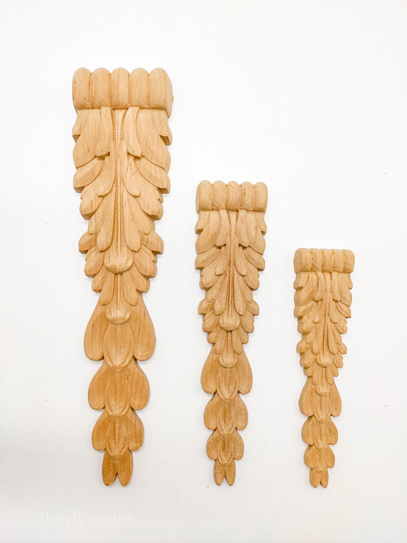 May include: Three wooden decorative pieces with a carved leaf design. The pieces are different sizes and are arranged in a row from largest to smallest.