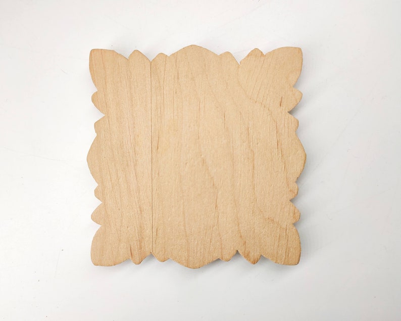 Puede incluir: Un letrero de madera en blanco con un borde decorativo y adornado. El letrero est&aacute; hecho de madera clara y tiene una superficie lisa y sin terminar.