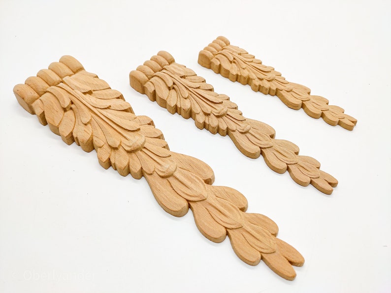 May include: Three wooden decorative pieces with a carved leaf design. The pieces are different sizes and are arranged in a row from largest to smallest.