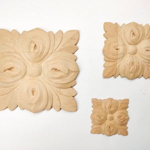 Puede incluir: Tres adornos decorativos de madera con un dise&ntilde;o floral. Los adornos son cuadrados y tienen un dise&ntilde;o tallado en relieve. El adorno m&aacute;s grande mide aproximadamente 10 cm de ancho.