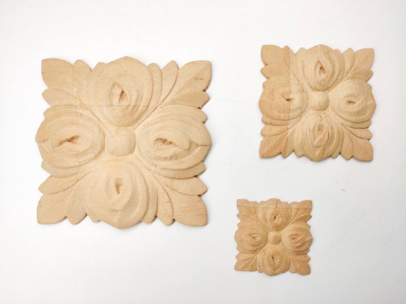 Puede incluir: Tres adornos decorativos de madera con un dise&ntilde;o floral. Los adornos son cuadrados y tienen un dise&ntilde;o tallado en relieve. El adorno m&aacute;s grande mide aproximadamente 10 cm de ancho.