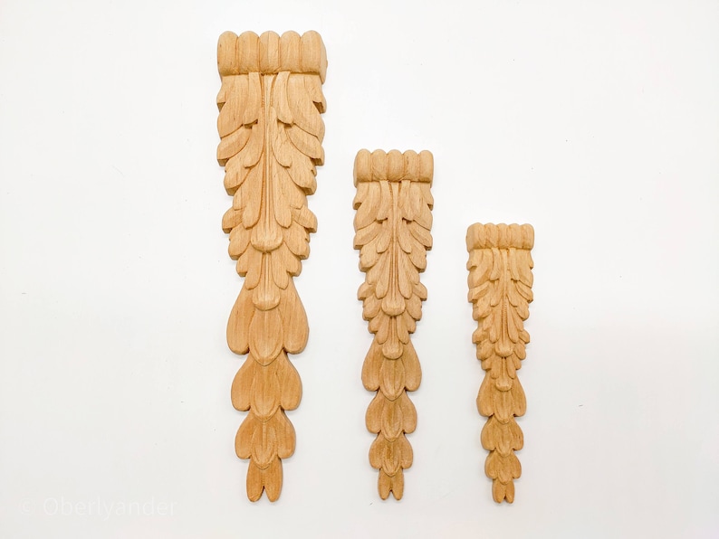 May include: Three wooden decorative pieces with a carved leaf design. The pieces are different sizes and are arranged in a row from largest to smallest.