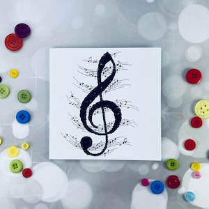 May include: A white card with a black treble clef and music notes printed on it.