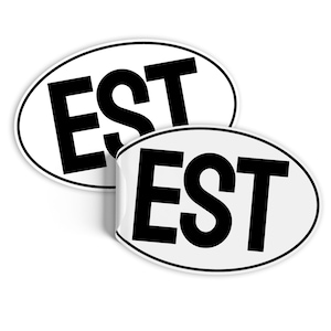 Może przedstawiać: Dwa białe owalne naklejki z czarnym tekstem, który na każdej naklejce brzmi "EST".