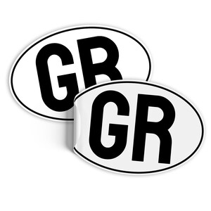 Może przedstawiać: Dwa białe owalne naklejki z czarnym napisem. Każda naklejka zawiera napis "GR" pogrubionymi, czarnymi literami.