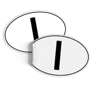 Może przedstawiać: Dwie białe owalne naklejki z czarną obwódką i czarną literą "I" pośrodku. Jedna naklejka jest częściowo odklejona, odsłaniając stronę klejącą. Naklejki są na białym tle.