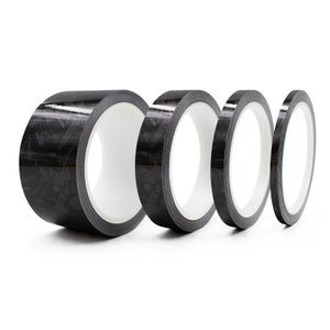 Op de afbeelding: Vier rollen zwarte koolstofvezeltape, elk met een andere breedte. De tape is ontworpen voor gebruik in een verscheidenheid van toepassingen, waaronder automotive, luchtvaart en industrie.