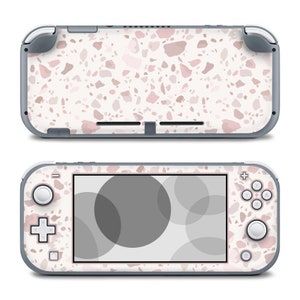 May include: A white and pink Nintendo Switch Lite console with a terrazzo pattern. The console has a black screen and gray buttons.