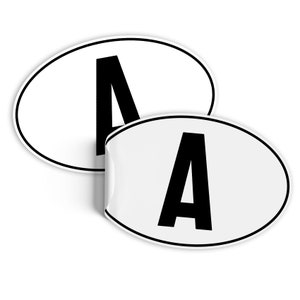 Może przedstawiać: Dwa białe owalne naklejki z czarną literą A nadrukowaną na każdym.