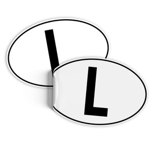 May include: Two white oval stickers with a black letter L printed on them. The stickers are partially overlapping.
