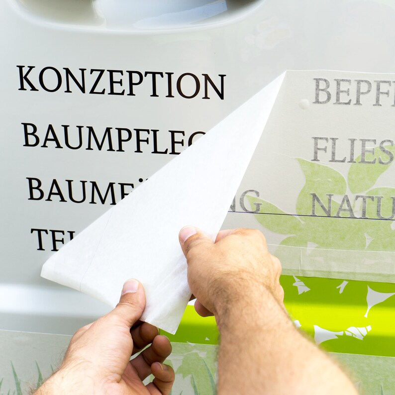 Puede incluir: Una persona est&aacute; aplicando una pegatina de vinilo blanco a una superficie verde y blanca. La pegatina tiene las palabras "BEPF", "FLIES", "NATU" y un dise&ntilde;o de hoja verde. La superficie tiene las palabras "KONZEPTION", "BAUMPFLEG", "BAUMF" y "TF" en negro.