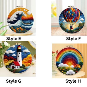 May include: Four different embroidery hoop art pieces. The first piece features a blue wave crashing against a yellow and orange sunset. The second piece features a hot air balloon with colourful balloons and a couple holding hands. The third piece features a white lighthouse with a red roof and a small house with a red roof. The fourth piece features a rainbow with a yellow sun and green hills.