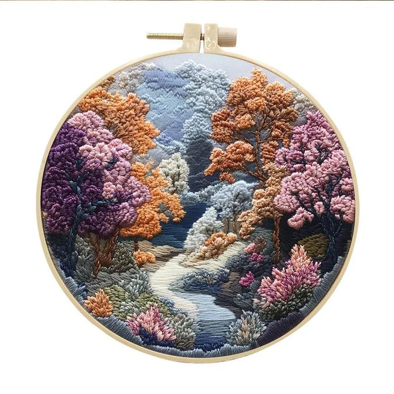 May include: A circular embroidery hoop with a colorful landscape scene. The scene features a winding path through a forest with trees in shades of purple, pink, orange, and blue.
