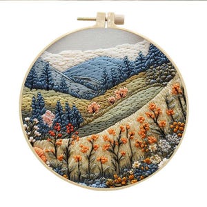 May include: Embroidered hoop art featuring a landscape scene with blue mountains, green hills, and orange flowers. The hoop is made of wood and has a natural finish.