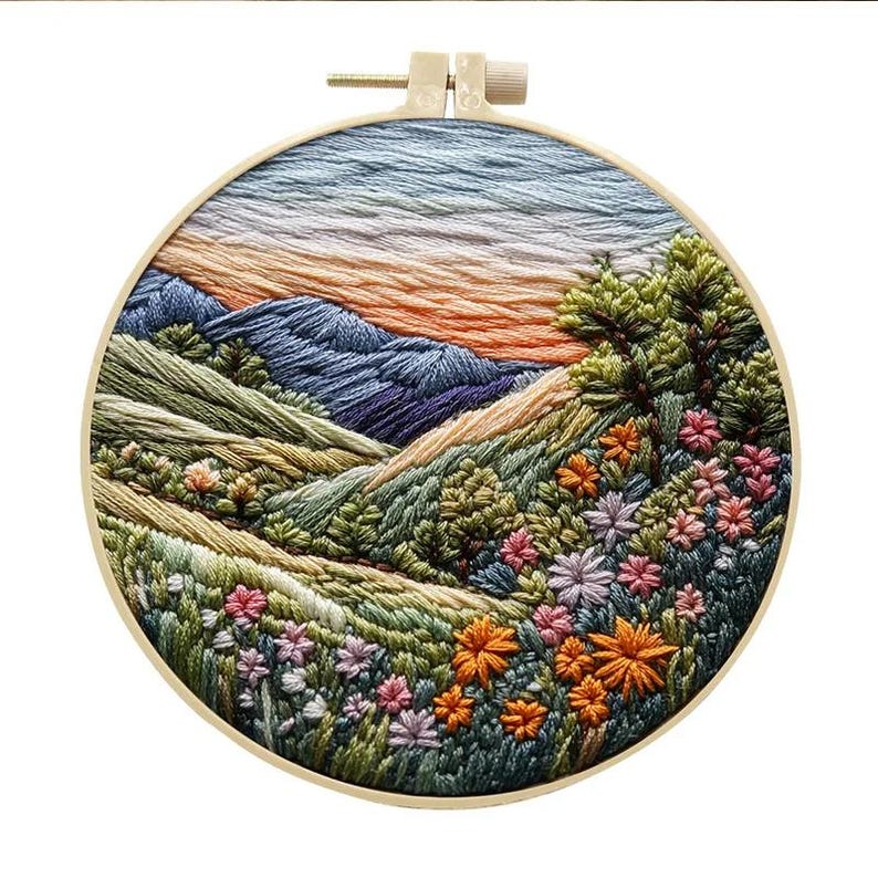 May include: Embroidered hoop art depicting a landscape with mountains, hills, and a field of flowers in shades of green, blue, orange, and pink.